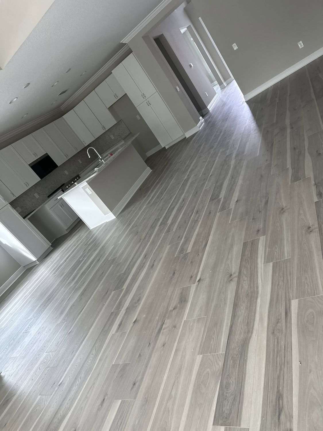 Gray wood-look luxury vinyl plank flooring installed through an open kitchen