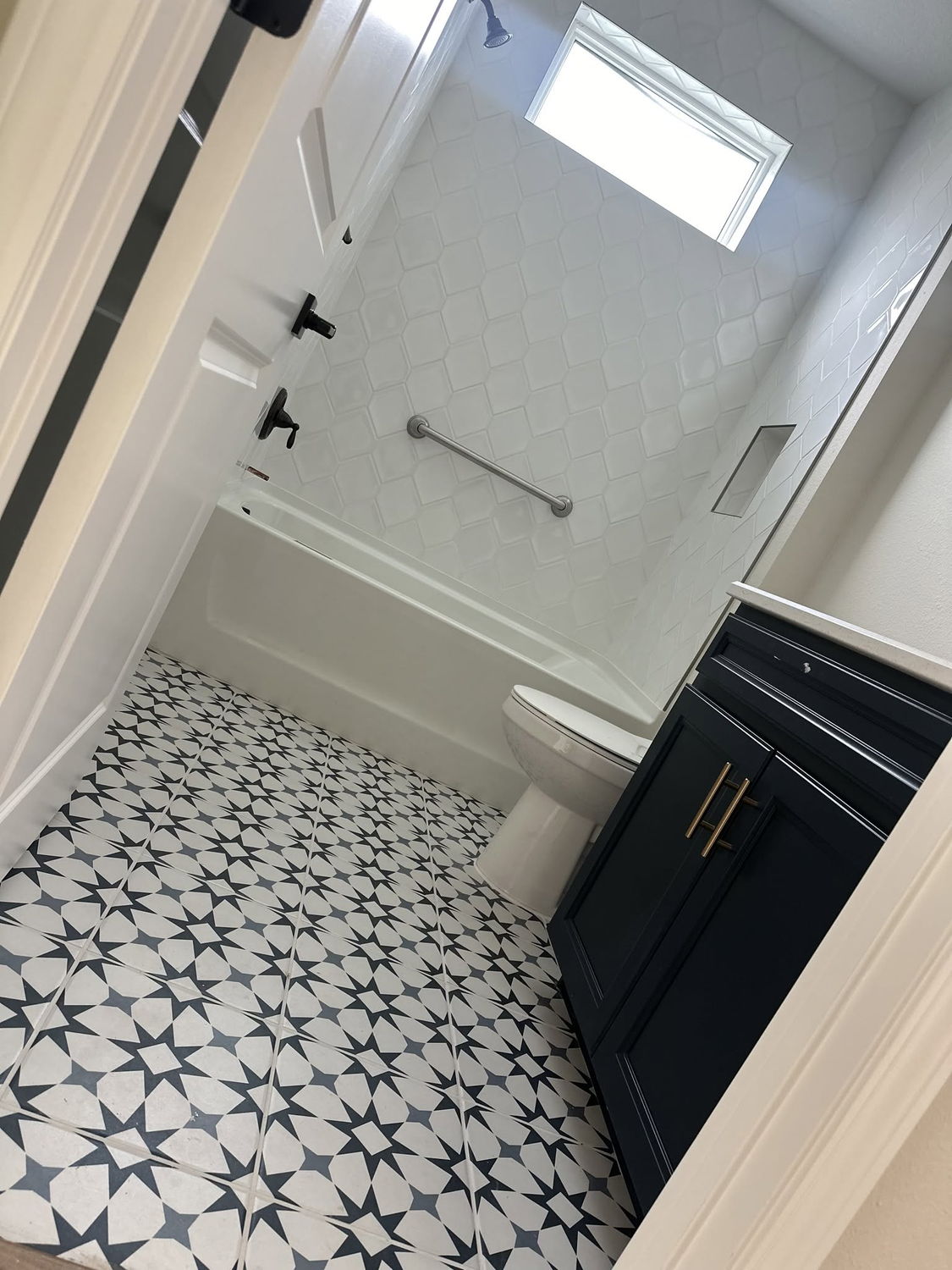 Black and white patterned tile bathroom floor with a navy vanity