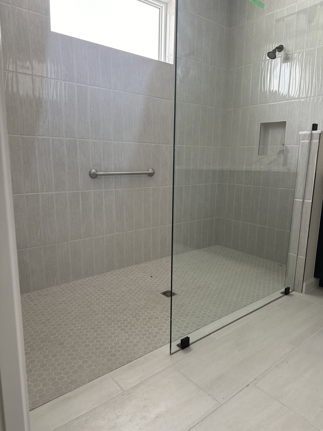 Light gray tiled walk-in shower with a hexagon tile floor