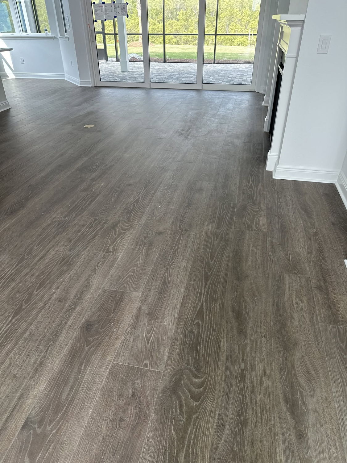 Dark wood-look vinyl plank flooring flowing toward sliding glass doors