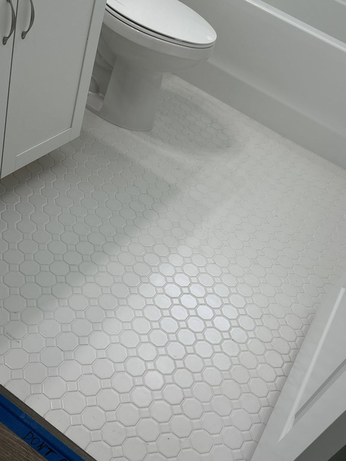 White hexagon tile bathroom floor installed around a pedestal toilet