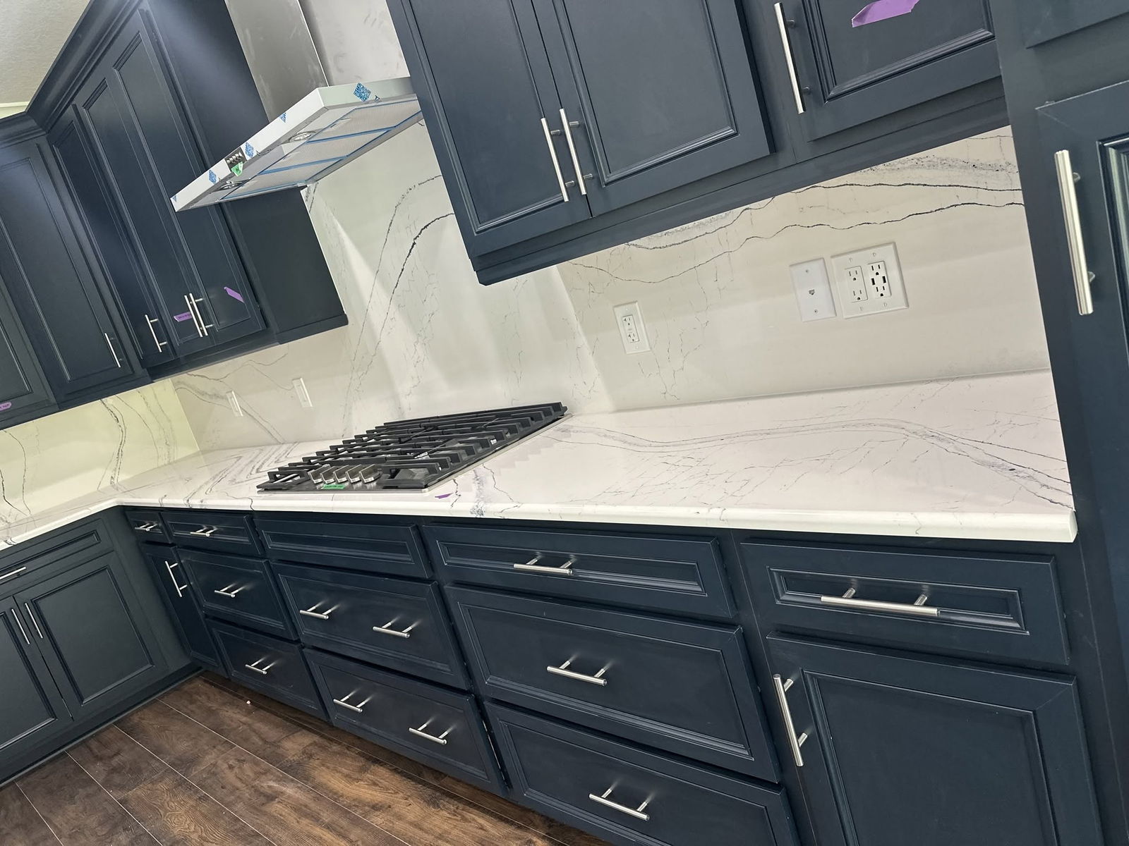 Navy kitchen cabinetry with quartz countertops and stainless hardware